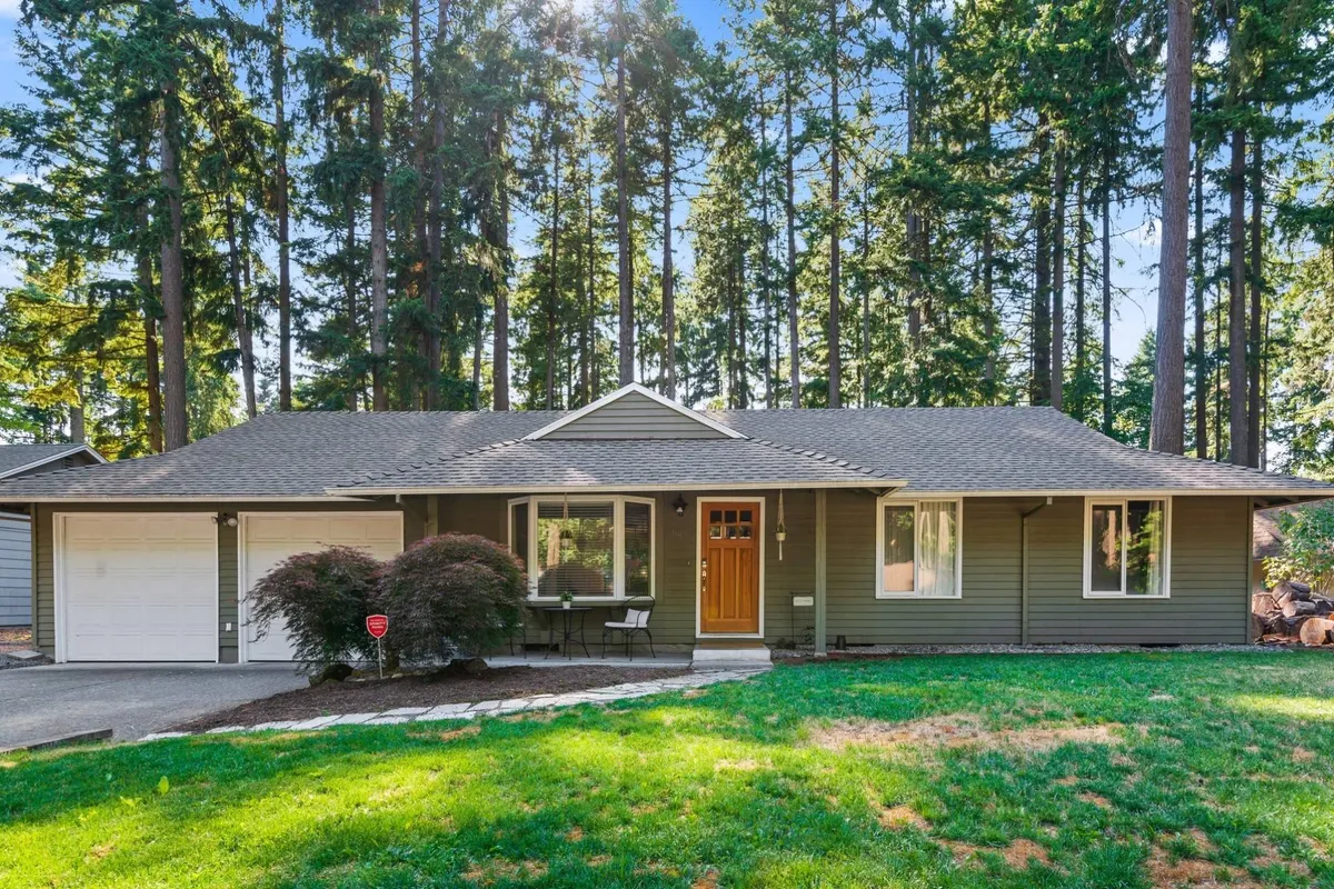 A view of the home’s front exterior showcasing the front door, large windows, a spacious porch, and a landscaped lawn. The scene suggests a welcoming entrance and a comfortable spot for relaxing and watching the neighborhood.