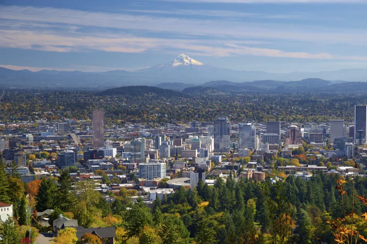 A scenic vista of the nearby downtown skyline framed by Mount Hood and lush forests, with visible walking trails inviting exploration. The image captures the spirit of outdoor adventure, city charm, and access to nature found near the property.